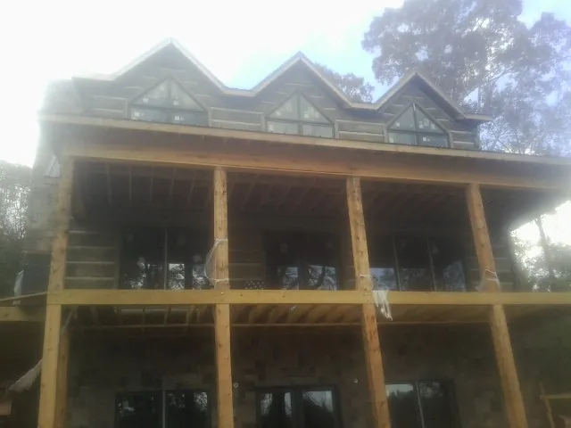 Dormers and porch framing on a large log home under construction — Roof Coating work by our crew in Madison