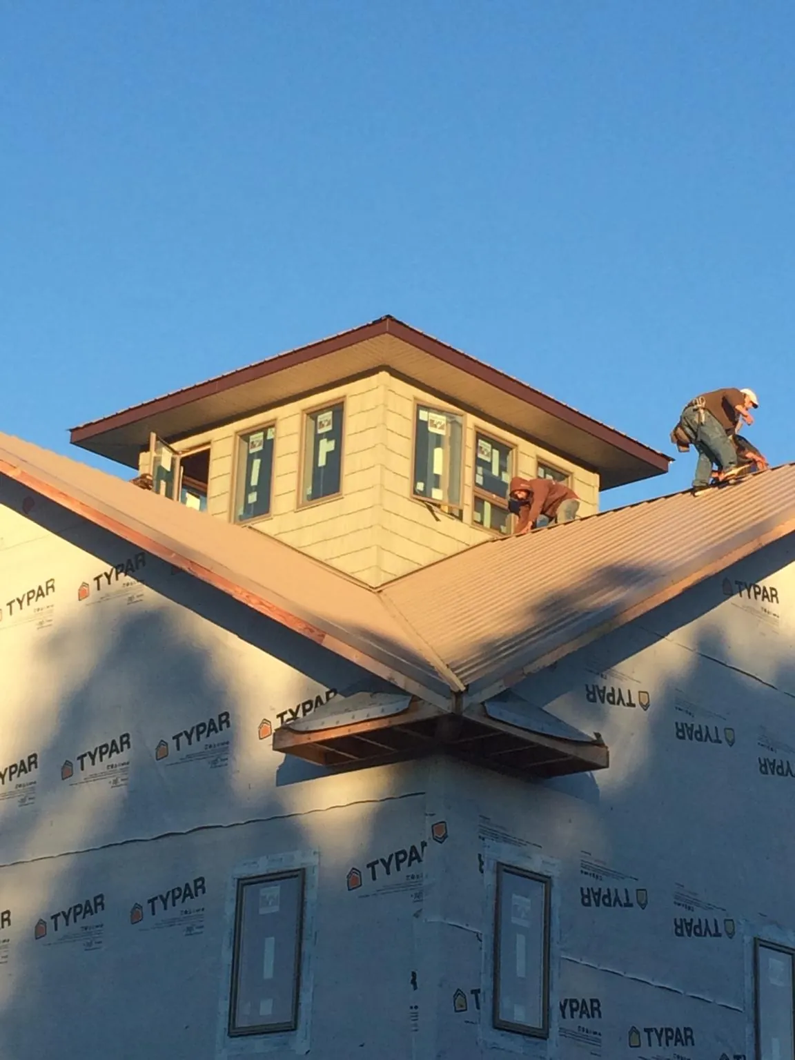 Roofers working around a rooftop cupola on a new metal roof at sunset — Roof Waterproofing in Madison by Roofing Brothers